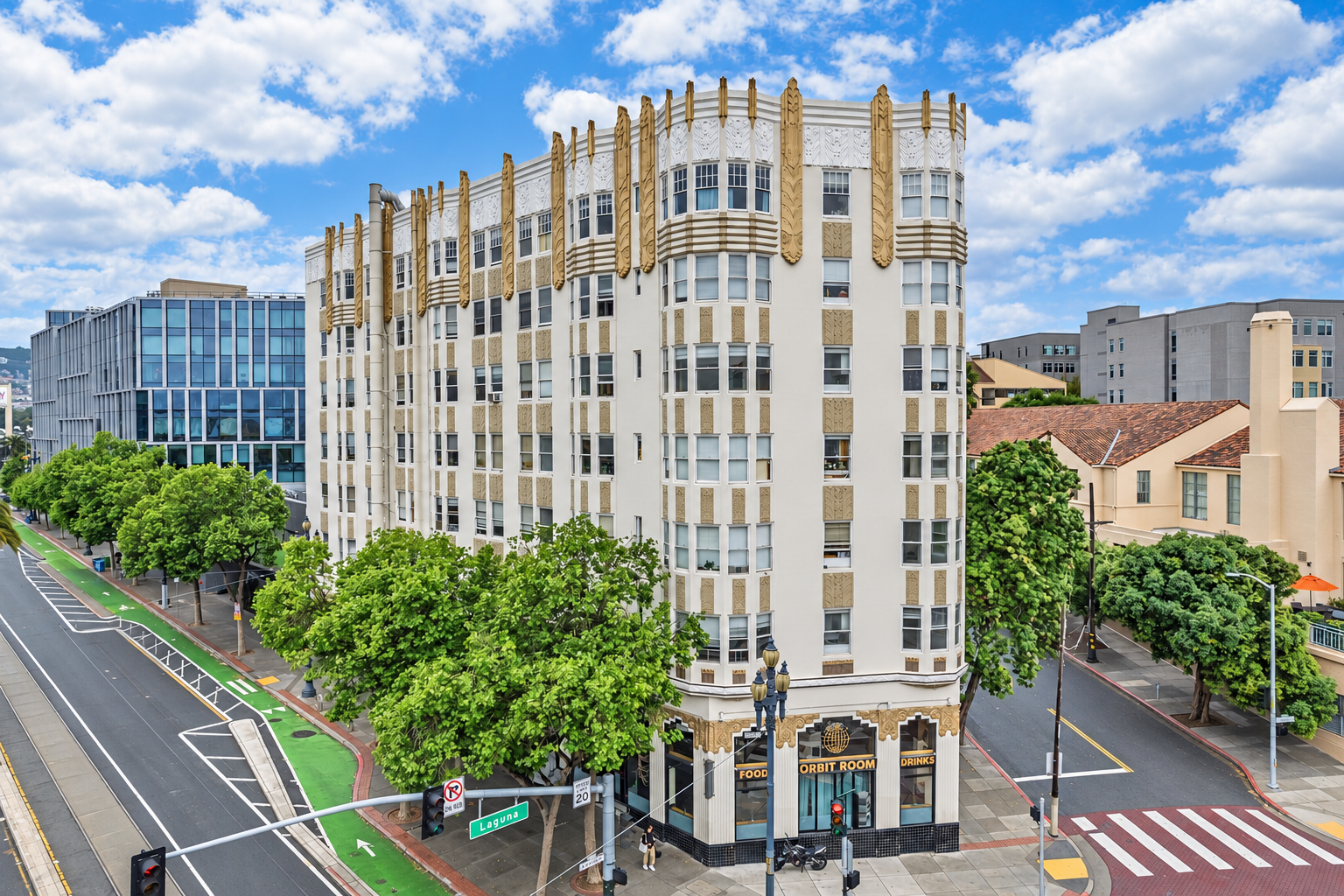 The white and gold Art Deco facade of 15 Hermann Street, framed by trees under a blue sky
